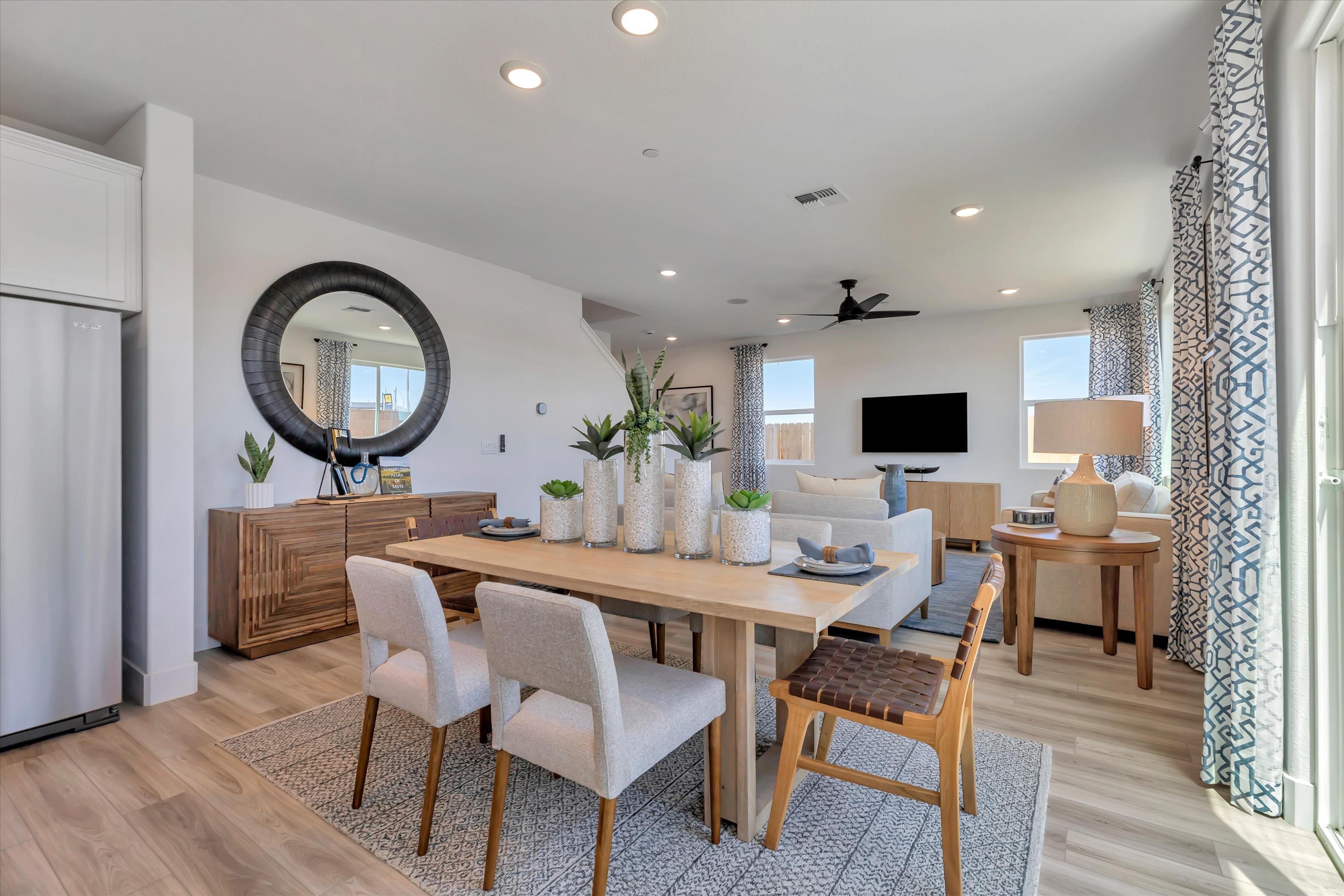 A dining room with a round mirror.
