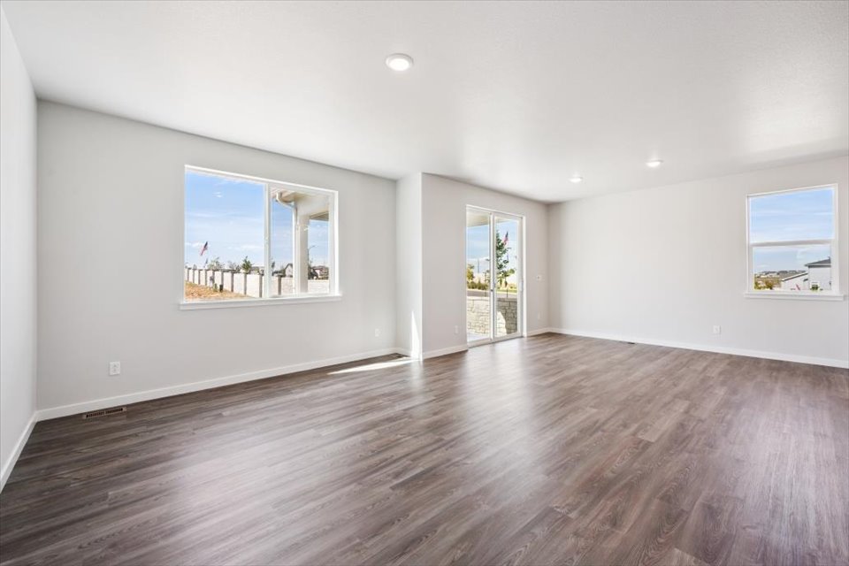 A large empty room with a wood floor and a large window.