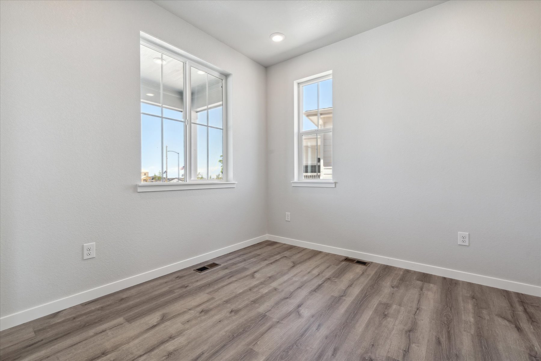 A room with a wood floor and a window with a white wall.
