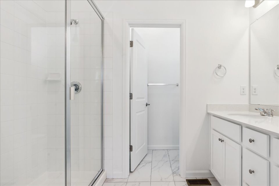 A bathroom with a shower unit and a sink.