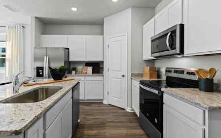 Davor Model Paired Home Kitchen with Marbled Counters and White Cabinets at The Landings at Pecan Park