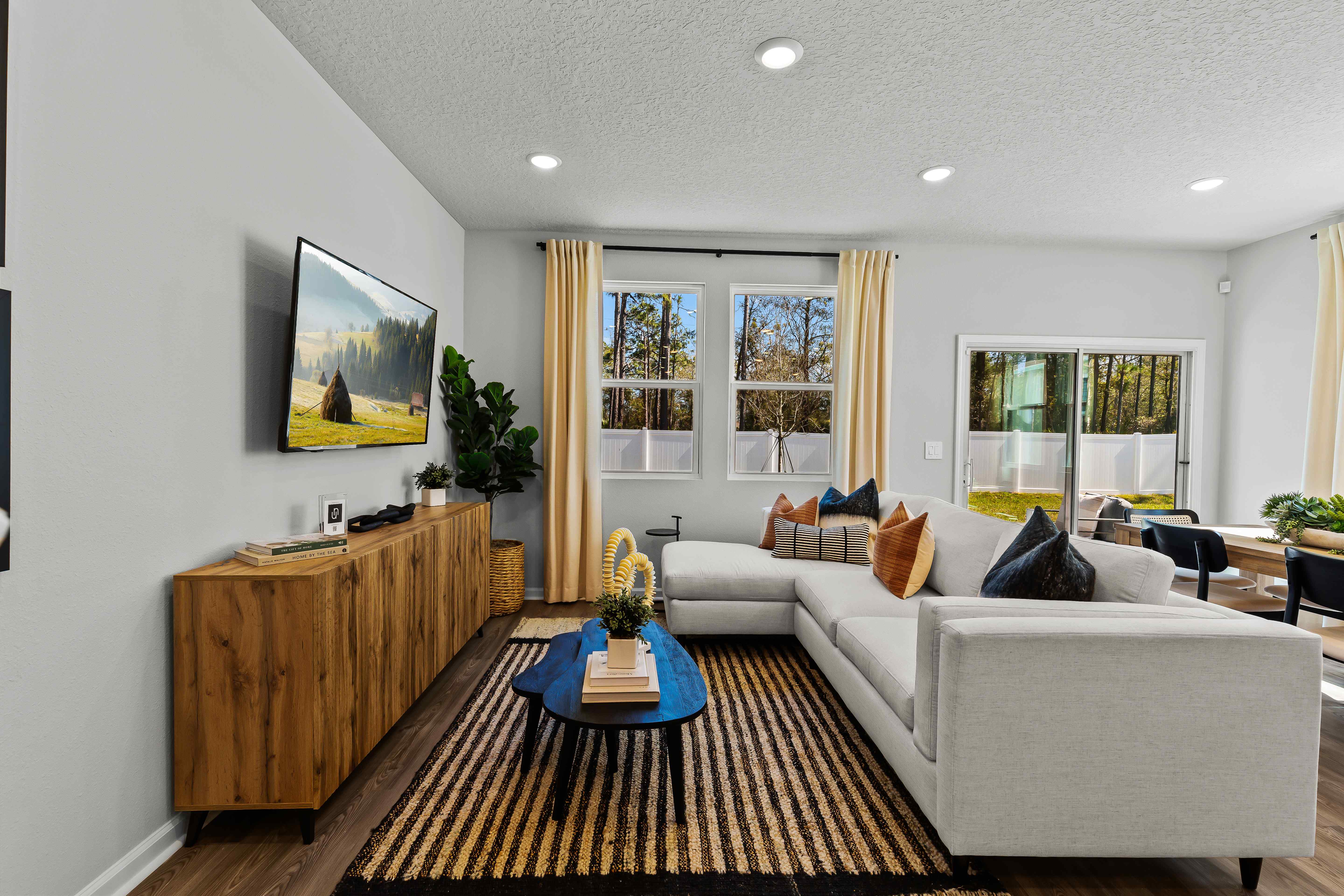 Davor Model Paired Home Living Room with Cream Couch and Black Table and Double Window at The Landings at Pecan Park