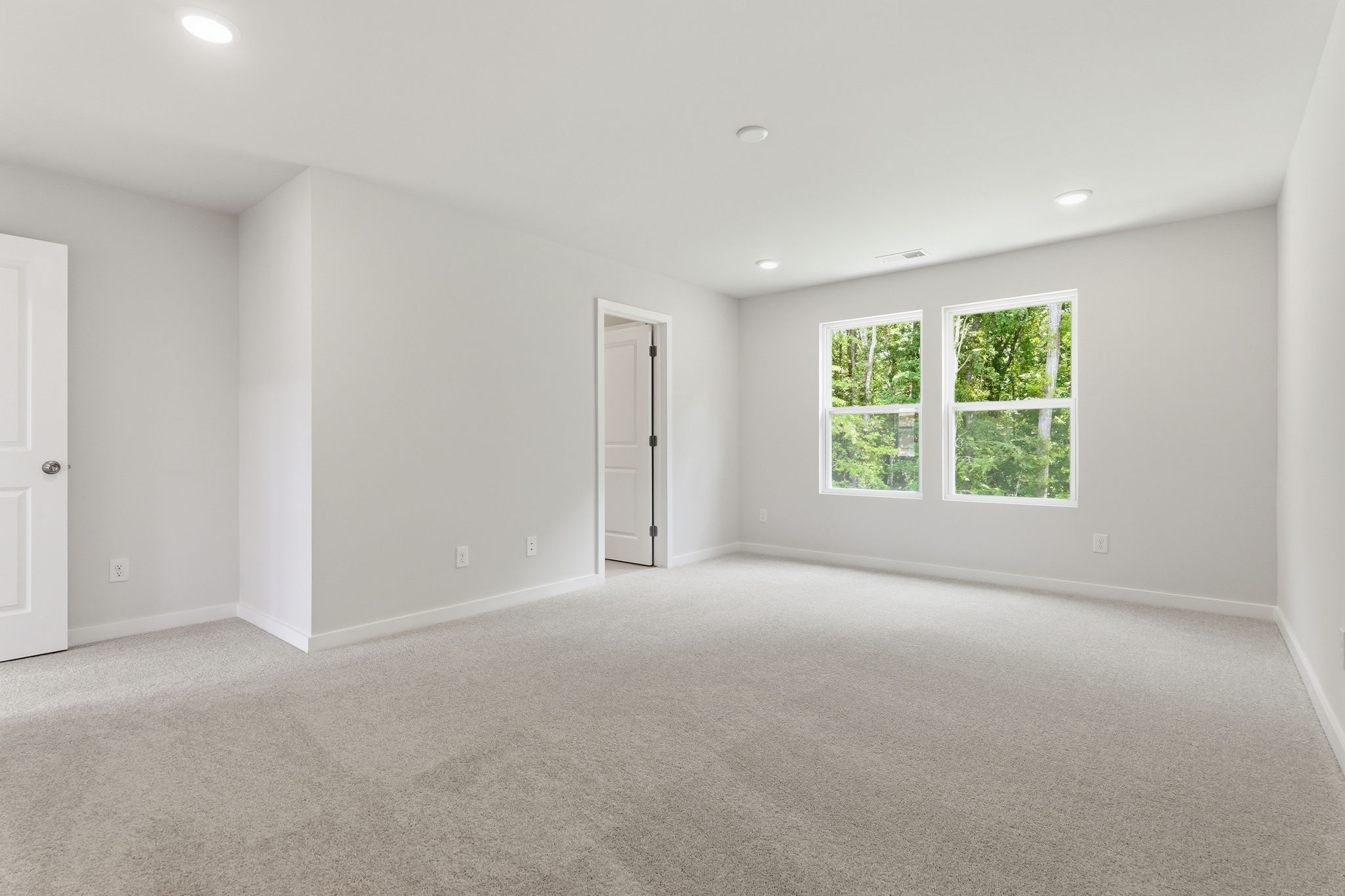A room with a window and a carpeted floor.