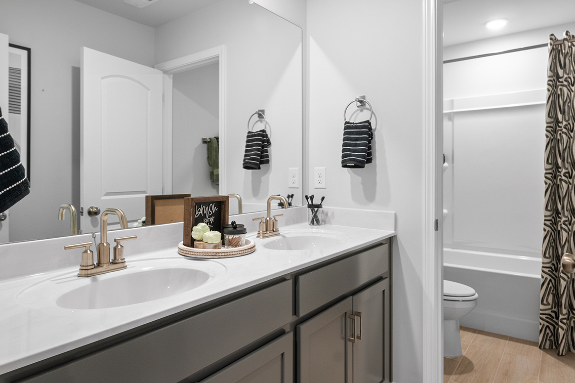 A bathroom with a sink toilet and mirror.