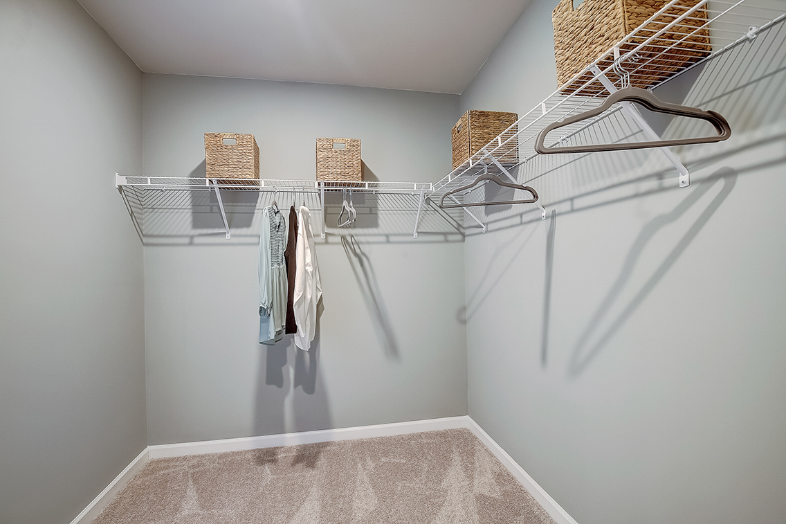 A white wall with a white shelf and a basket with clothes.