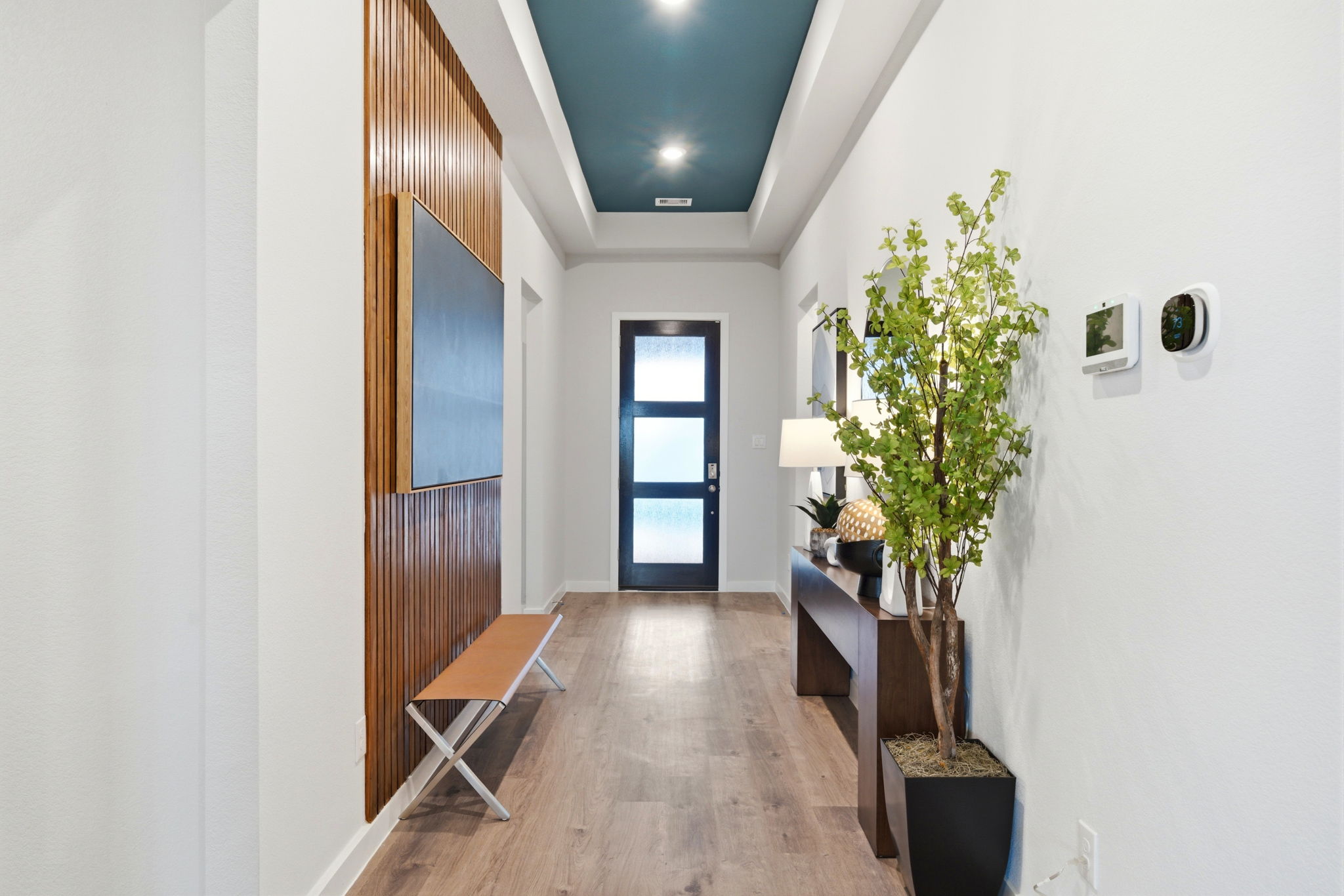 A hallway with a bench and a plant in it.