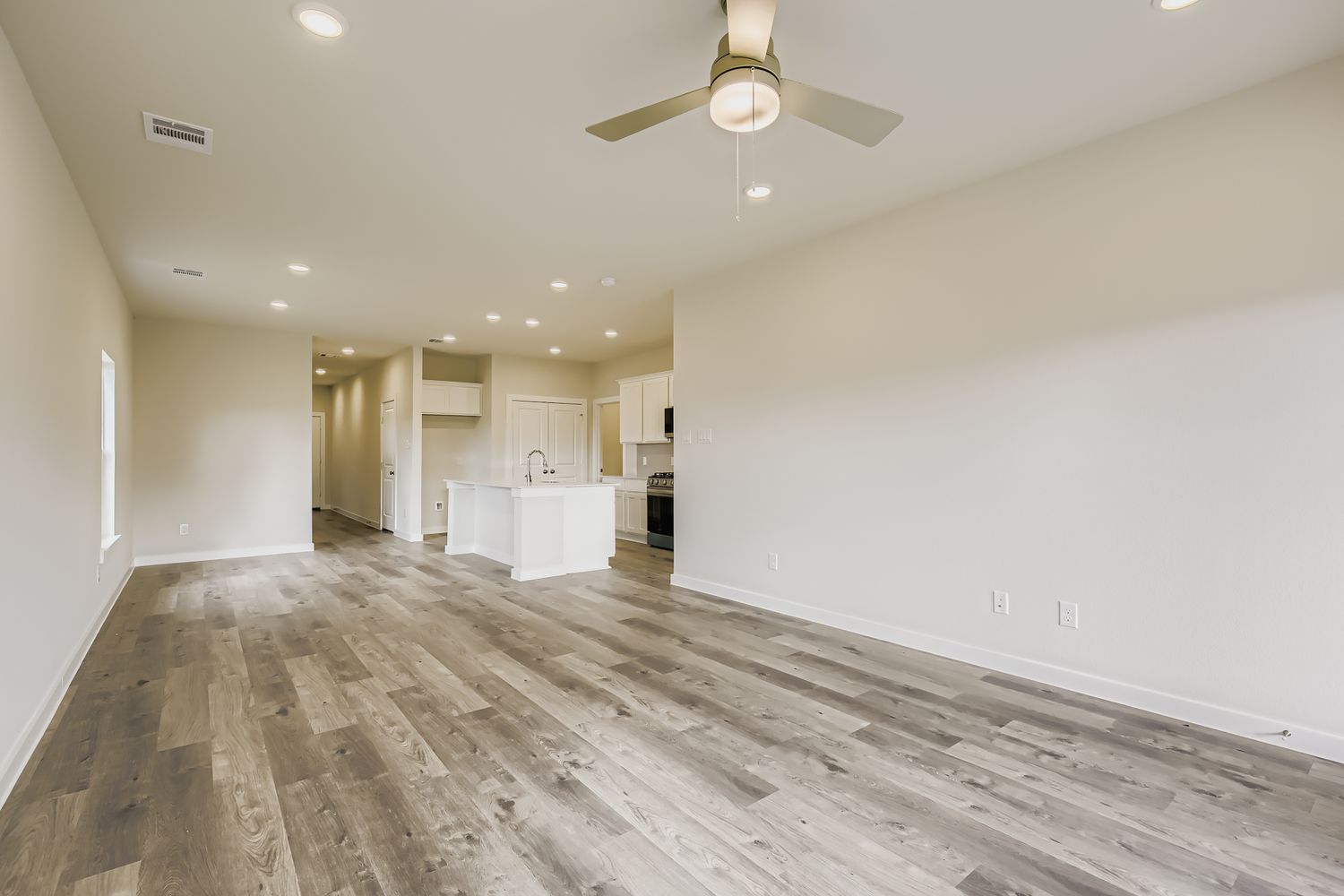 A large empty room with a wood floor and a ceiling fan.
