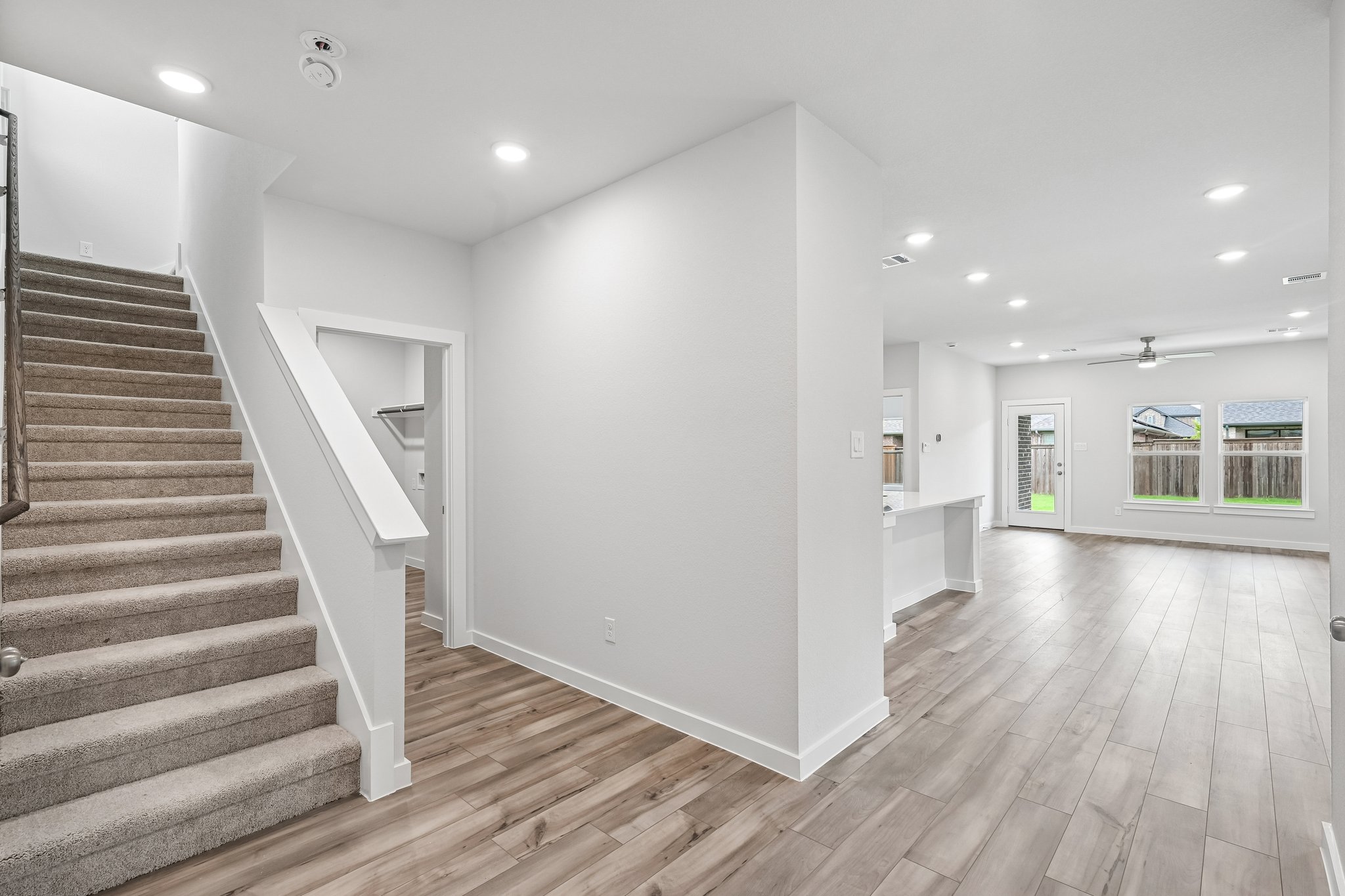A large white room with a wood floor and a staircase.