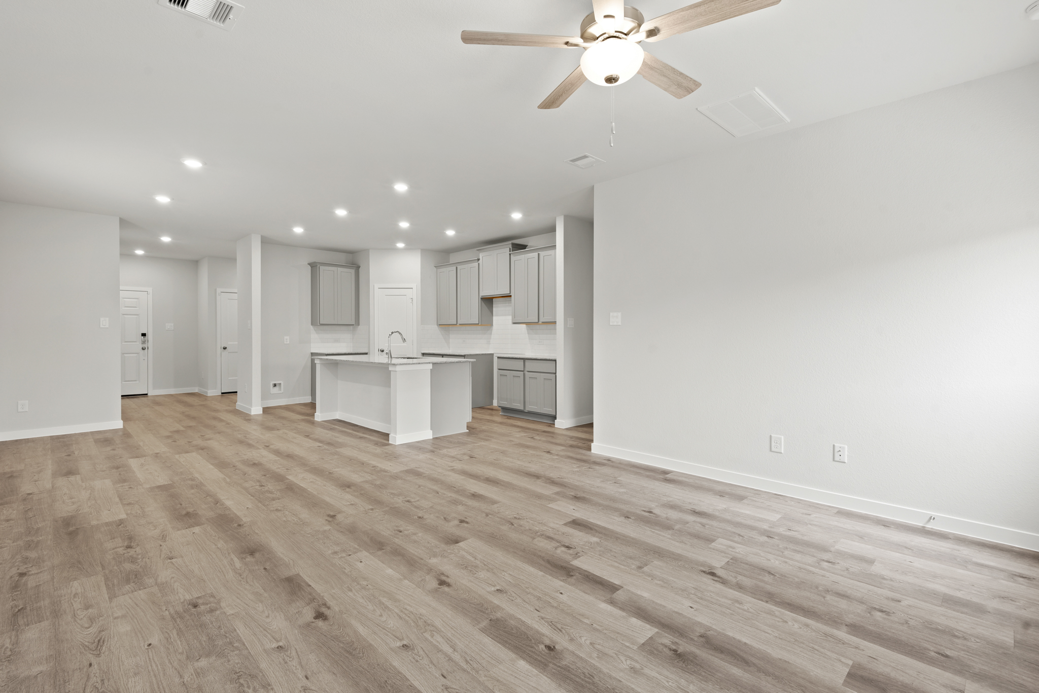 A large empty room with a wood floor and a ceiling fan.