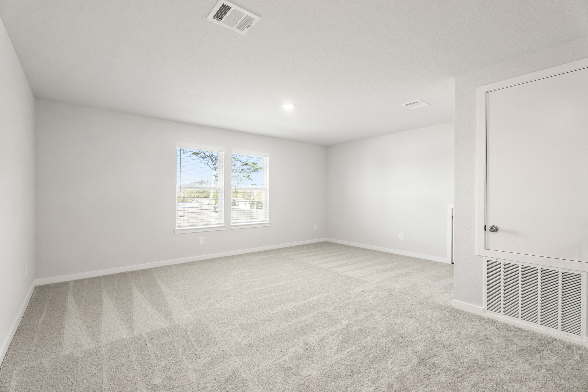 A room with a white door and a white wall with a window.