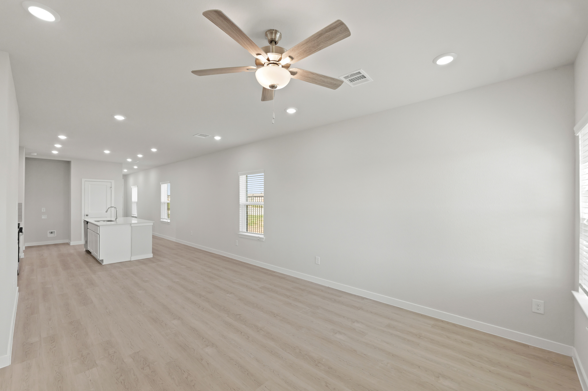 A room with a ceiling fan and wood floors.
