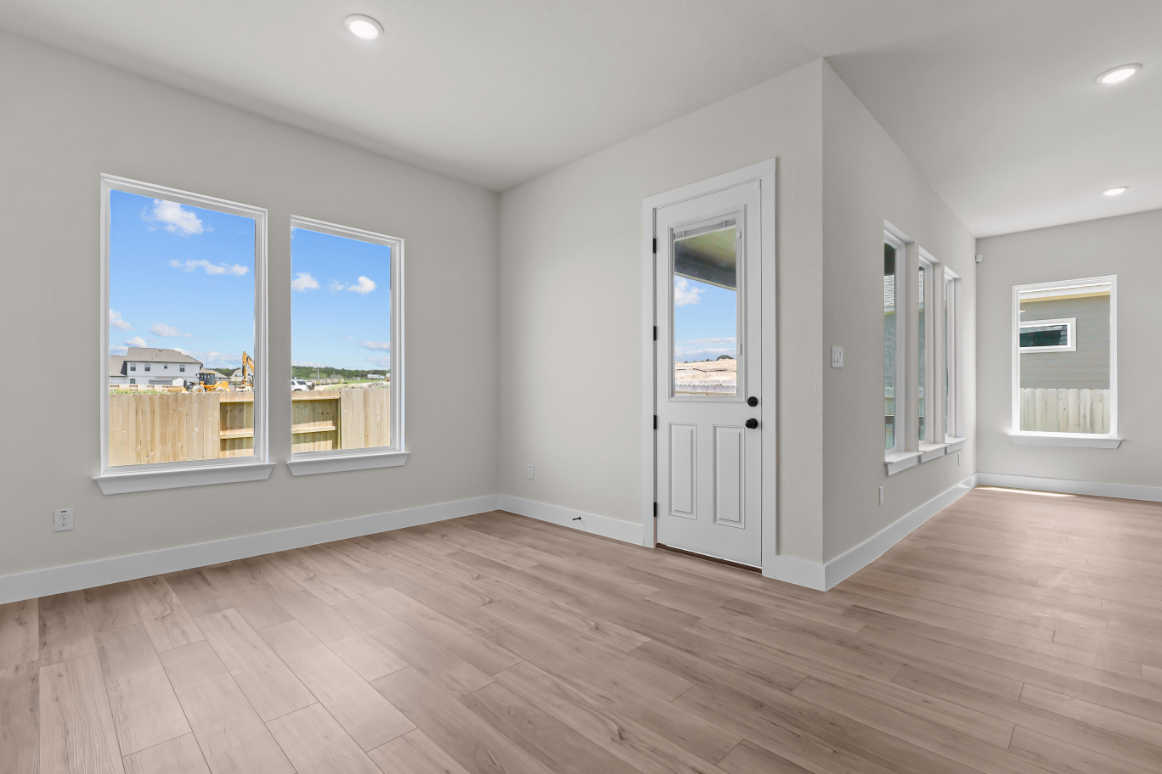 A room with white walls and a wood floor with a door and a window with a view of.