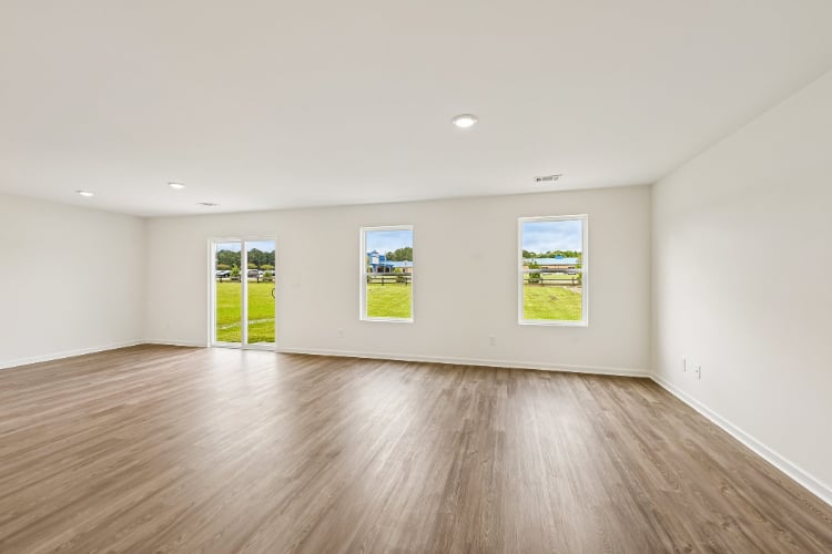 A room with a wood floor and a wood floor with a few paintings on the wall.